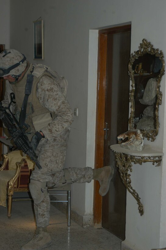 AR RAMADI, Iraq (March 19, 2005) - Nineteen-year-old Lance Cpl. Joshua A. Shores, squad automatic gunner, 1st Squad, 1st Platoon, Company A, 1st Battalion, 5th Marine Regiment, of New Richmond, Wis., kicks a door open while searching buildings for weapons caches and insurgents with his company. The 6-foot-7-inch 200-pound Marine's specialty is kicking doors open and creating entrances where there are none, which makes him a valuable asset when clearing houses. Photo by Cpl. Tom Sloan