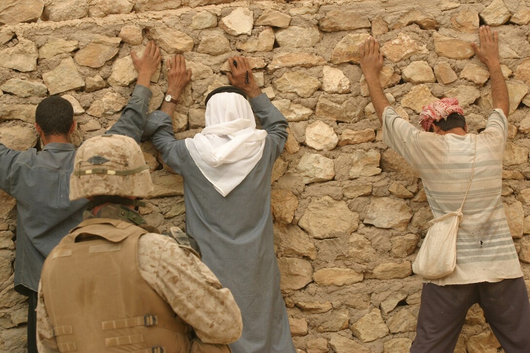CAMP HADITHAH, Iraq - A Marine with Company L, 3rd Battalion, 25th Marine Regiment guards farmers along a nearby road while his platoon conducts a search for roadside bombs and mortar positions, April 19.  The search was prompted by a recent mortar attack that hit the dam.  Two Iraqis were found with a rifle, explosives and bomb making material.  U.S. Marine Corps photo by Sgt. Stephen D'Alessio (RELEASED)