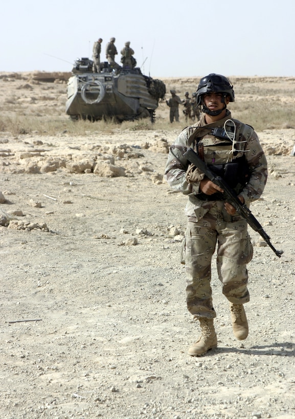THAR THAR REGION, Iraq - An Iraqi soldier patrols in front of an amphibious assault vehicle through the wasteland fields here June 19 in search of weapons and explosives.  The Iraqi soldiers assisted U.S. personnel during Operation Dagger, a five-day long effort to rid regions north of Fallujah of insurgent activity.