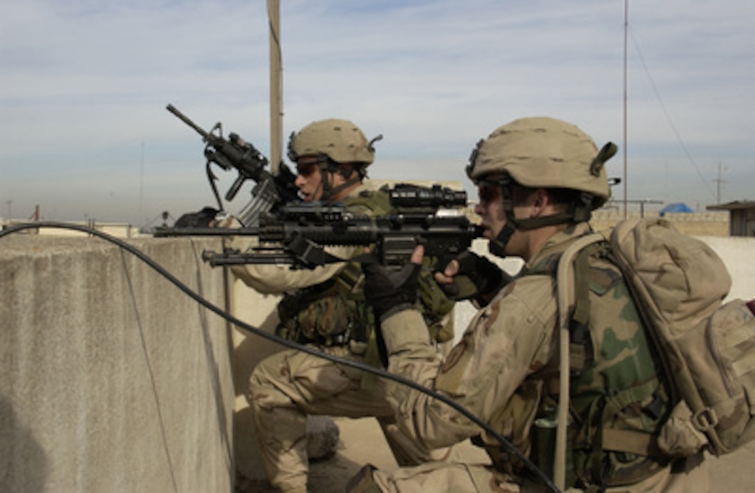 U.S. Army soldiers scan for enemy activity from a rooftop in eastern Mosul, Iraq, on Jan. 1, 2005. The soldiers are assigned to Alpha Company, 1st Battalion, 24th Infantry Regiment, 1st Brigade, 25th Infantry Division, Stryker Brigade Combat Team. The company is providing security while an Explosive Ordnance Disposal team examines a weapons cache found by Iraqi commandos and U.S. Special Forces. 