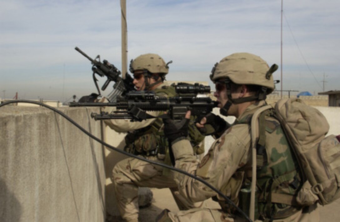 U.S. Army soldiers scan for enemy activity from a rooftop.