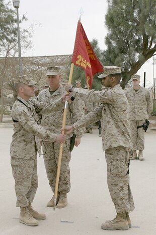 AL ASAD, Iraq -- First Lt. Michael K. Mishoe Jr., incoming commanding officer and Corning, Calif., native, receives the company guidon from Capt. Tom Chhabra, outgoing commander originally from West Windsor, N.J., as he assumes command of Headquarters and Service Company, Provisional Security Battalion on April 20 at a ceremony held outside the Base Defense Operations Center here.  The passing of the guidon, or colors, represents the passing of authority and responsibility from one commander to the other.