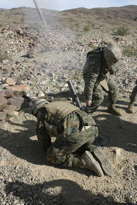 MARINE CORPS AIR-GROUND COMBAT CENTER TWENTYNINE PALMS, Calif. - Two mortarmen with Company A, 1st Battalion, 6th Marine Regiment cover their ears and avert their eyes after firing their 60mm mortar weapons system aboard Range 410A here.  The mortarmen are participating in a Revised Combined Arms Exercise to prepare them for a deployment to Iraq in March.