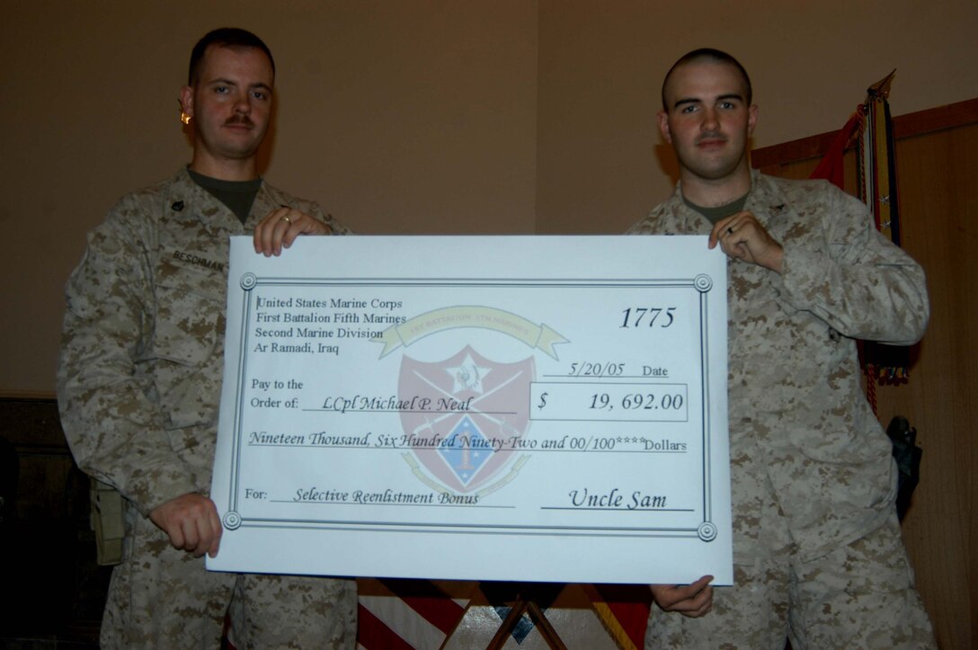 CAMP HURRICANE POINT Ar Ramadi, Iraq (May 20, 2005) -Lance Cpl. Michael P. Neal, a machine gunner with 1st Battalion, 5th Marine Regiment's Jump Platoon, and Staff Sgt. William E. Beschman Jr., the infantry battalion's career retention specialist, hold a giant reenlistment bonus check during a ceremony here. The 21-year-old from Country Club Hills, Ill., swore to devote four more years of service to Corps and country. The 2001 Hillcrest High School graduate received a reenlistment bonus of $19,692, which is tax-free and will be paid in a lump sum. North and his two-man camera crew covered the event, which will later appear on the Fox News show "Oliver in Iraq." Photo by: Cpl. Tom Sloan