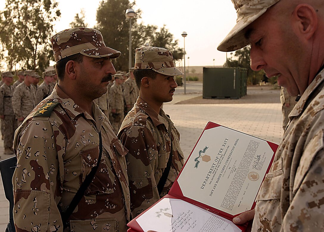 Camp Ripper, Al Anbar, Iraq (May 20, 2005)-- Capt. Salah Ati Ne'emah 43 of Baghdad and 20-year-old Basra, Iraq native Cpl. Ahmed Jalil Mani'a with 7th Iraqi Reconnaissance Battalion listen attentively as the awards for their actions are read aloud in Arabic. (Official USMC Photo by Corporal Ken Melton)