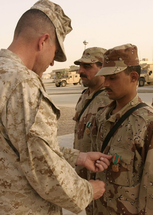 Camp Ripper, Al Anbar, Iraq (May 20, 2005)-- Col. Davis RCT-2 commanding officer, presents Cpl. Ahmed Jalil Mani'a a 20-year-old Basra, Iraq native, with the Navy and Marine Corps Achievement Medal for his actions during a mission in Iraq. (Official USMC Photo by Corporal Ken Melton)