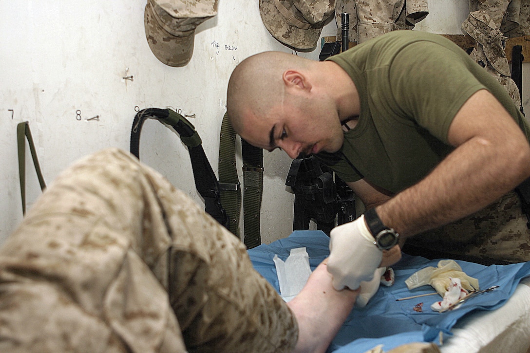 CAMP BAHARIA, Iraq - Hospitalman 3rd Class Chad Jorges, a corpsman with 1st Battalion, 6th Marine Regiment's battalion aid station, removes an ingrown toenail from a Marine's foot here June 7.  The 23-year-old Coon Rapids, Minn. native and fellow corpsmen treat conditions such as gastrointestinal problems, insect bites, and acute illnesses.