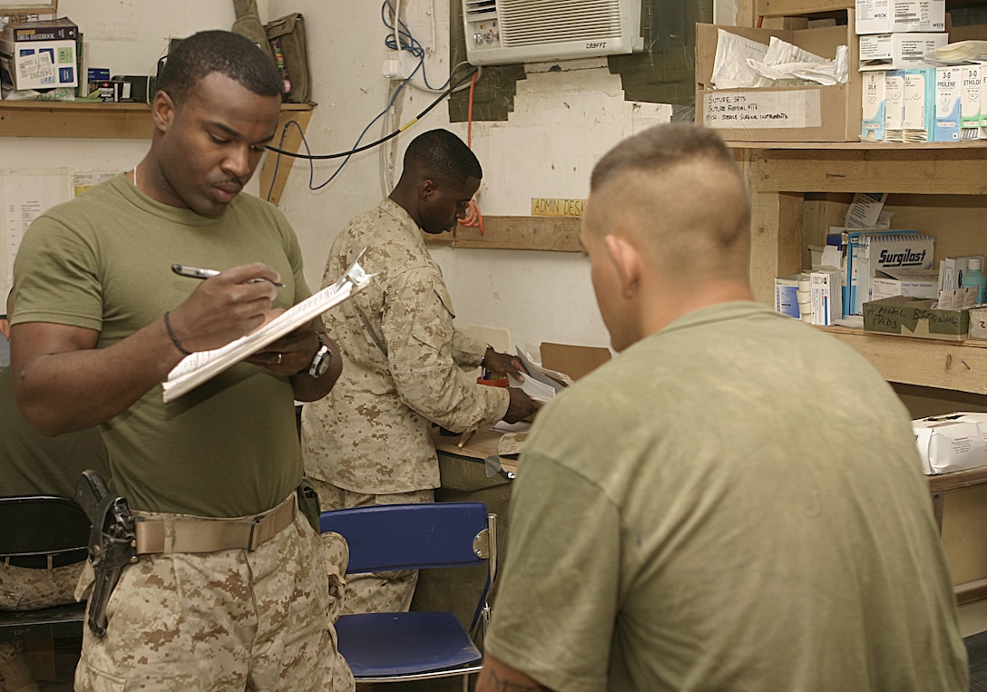 CAMP BAHARIA, Iraq - Hospitalman Donald Martin, a corpsman with 1st Battalion, 6th Marine Regiment's battalion aid station, jots down information on a Marine patient before treating him here June 7.  Martin and his fellow corpsmen treat conditions such as gastrointestinal problems, insect bites, and acute illnesses.
