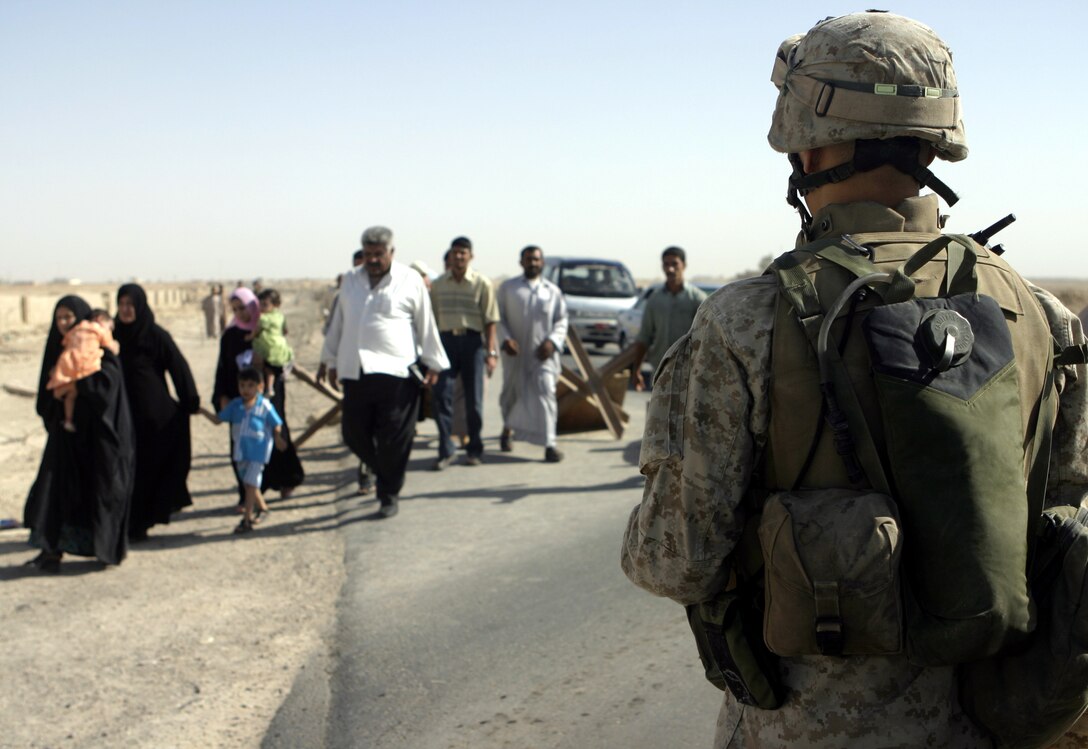 FALLUJAH, Iraq - A Marine with 1st Battalion, 6th Marine Regiment watches a crowd of Iraqis file past his check station in northern Fallujah's Entry Control Point-2 June 10.  Iraqi Security Forces and 1st Battalion, 6th Marine Regiment personnel man this ECP and prevent weapons, explosives and insurgents from entering the city.