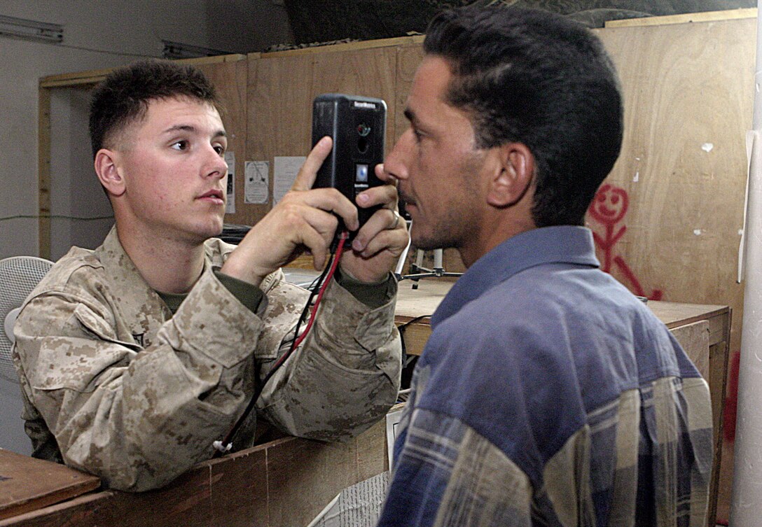 FALLUJAH, Iraq - Lance Cpl. Tyler Duffin, a Marine with 1st Battalion, 6th Marine Regiment who helps man northern Fallujah's Entry Control Point-2, uses an iris scanner to photograph an Iraqi man's eye June 10 before issuing him a new ID card.  The 20-year-old Michigan City, Ind. native works alongside Iraqi Security Forces to prevent weapons, explosives and insurgents from entering the city.