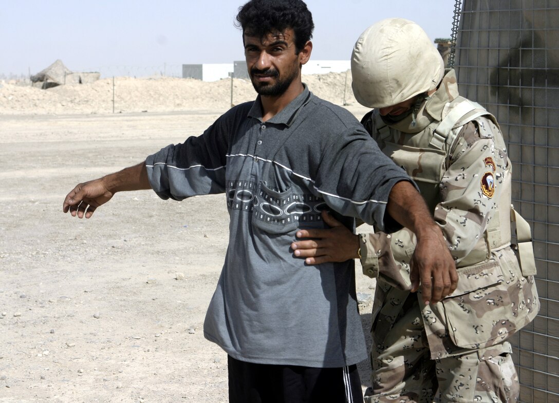 FALLUJAH, Iraq - An Iraqi soldier frisks a local man before allowing him through a checking station in northern Fallujah's Entry Control Point-2 June 10.  Iraqi Security Forces and 1st Battalion, 6th Marine Regiment personnel man this ECP and prevent weapons, explosives and insurgents from entering the city.
