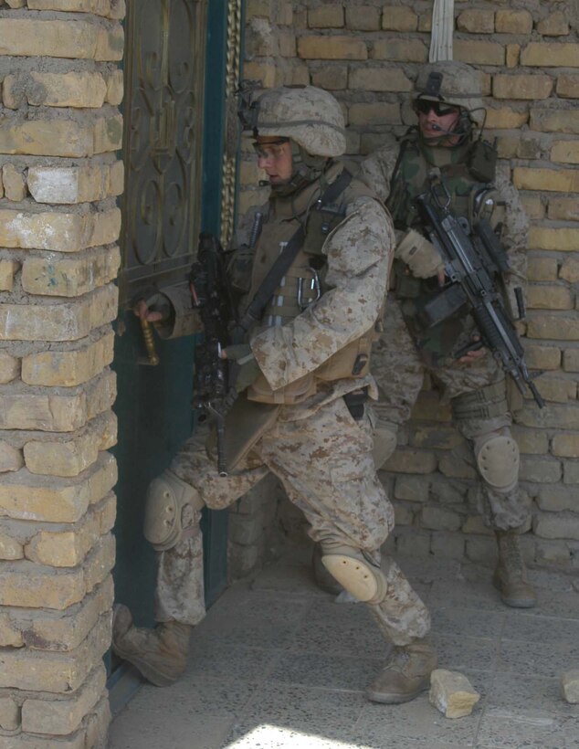 AR RAMADI Iraq (June 14, 2005) - Sergeant Tim R. Cyparski, a rifleman and the section leader for 1st Section, 1st Mobile Assault Platoon, Company W, 1st Battalion, 5th Marine Regiment, attempts to enter a house here during a mission while his comrade, Sgt. Michael A. Burgess, a 28-year-old assault man from Willoughby, Ohio, provides security. Insurgents attacked 27-year-old Cyparski from Erie, Pa., and his fellow warriors with an improvised explosive device during a presence patrol they executed in the southern portion of the city. No one was hurt and no vehicles were damaged. Photo by: Cpl. Tom Sloan