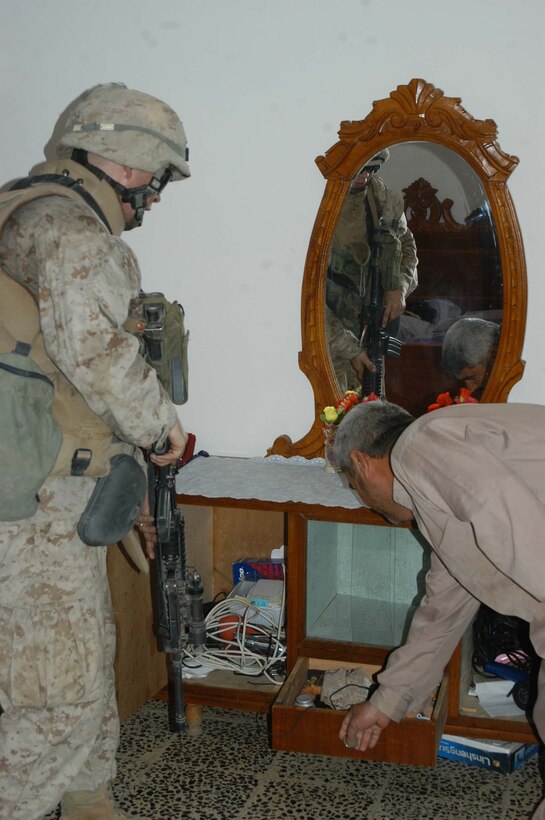 AR RAMADI Iraq (June 14, 2005) - Lance Cpl. Levi S. Samuels, a machine gunner with 1st Section, 1st Mobile Assault Platoon, Company W, 1st Battalion, 5th Marine Regiment, checks for threatening material in an Iraqi man's home during a mission here. Insurgents attacked the 19-year-old from Huntsville, Ark., and his fellow Marines with an improvised explosive device during a presence patrol they executed in the southern portion of the city. No one was hurt and no vehicles were damaged. Photo by: Cpl. Tom Sloan