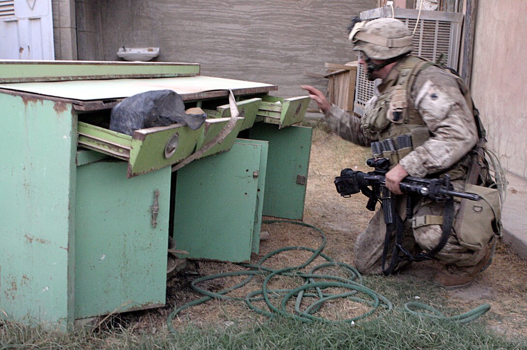 FALLUJAH, Iraq - Lance Cpl. Corey Bloomfield, a rifleman with 1st Platoon, Company B, 1st Battalion, 6th Marine Regiment, searches for munitions and explosives outside a house here Aug. 20 during Operation Hard Knock.  The 25-year-old Tecumseh, Mich. native, fellow Marines and Iraqi Security forces have conducted several of these operations since June to search for weapons and gather census data on the local citizens.
