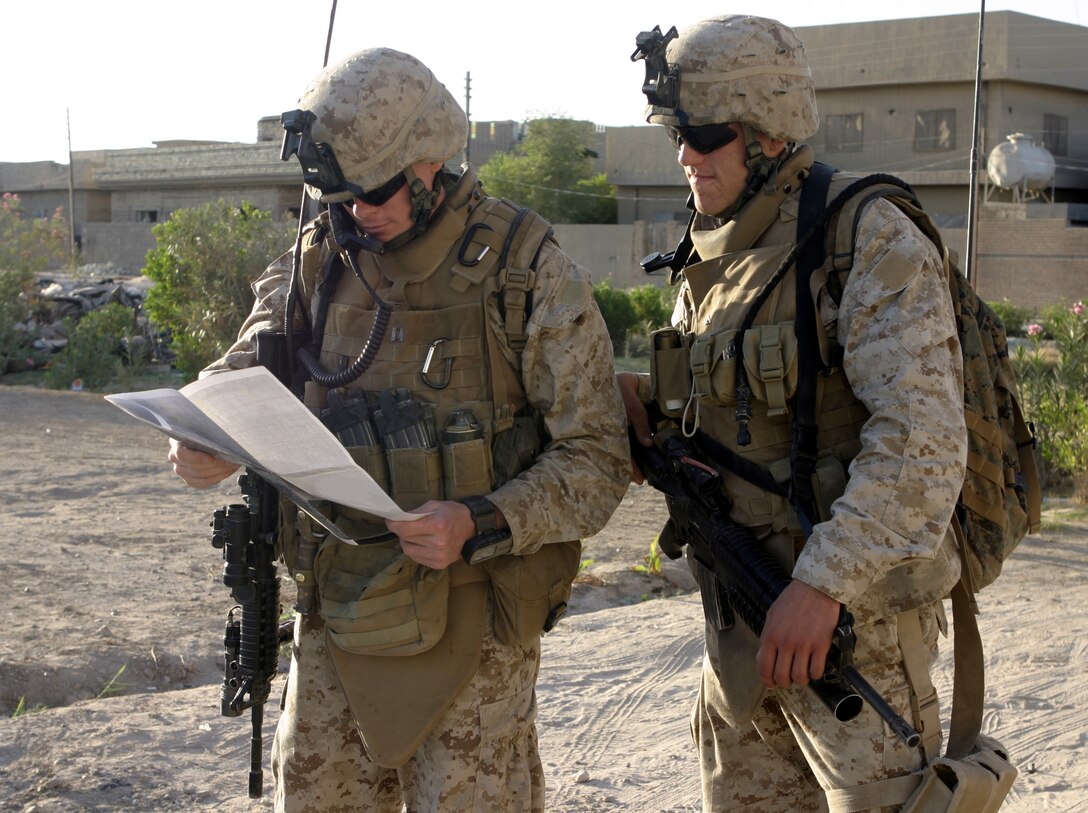 FALLUJAH, Iraq - Captain Seth Munson, a forward air controller with 1st Battalion, 6th Marine Regiment, left, and Lance Cpl. Michael Little, his radio operator, peer down at a street map here Aug. 20 during Operation Hard Knock.  Both Marines accompanied Company B, 1st Battalion, 6th Marine Regiment personnel and Iraqi Security Forces as they searched for weapons inside homes here and gathered census data on the populace.