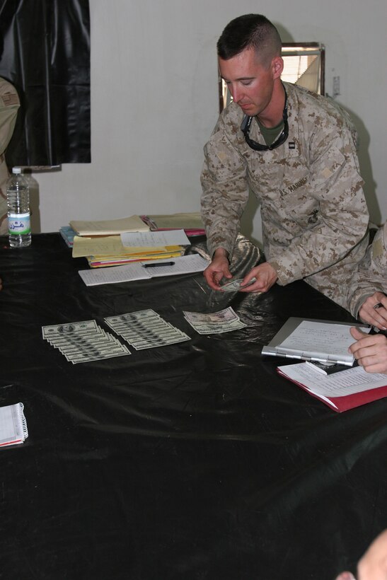 Captain Richard Belliss, operational lawyer, staff judge advocate, 2nd Marine Division, counts out $2,500 before giving it to an Iraqi citizen at the Fallujah Liaison Team site April 20. More than 200 Iraqi citizens went to the FLT to file claims for damaged personal property, injuries and deaths as a result of combat operations conducted by coalition forces during Operation Iraqi Freedom.