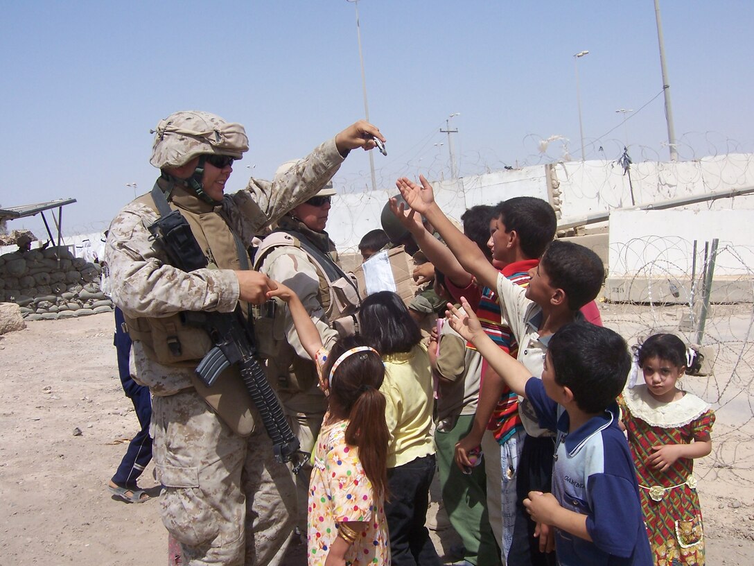 Lance Cpl. Andrew Champion, Chaplain's Assistant, Regimental Combat Team 8, passes out toys June 14 in Fallujah, Iraq. Champion, of Waltham Mass., coordinates regular distribution of toys, school supplies, and clothing as part of the RCT8 presence in Fallujah. Generous Americans and family members send these items on a regular basis to Iraq, and the items are sorted and distributed to children.