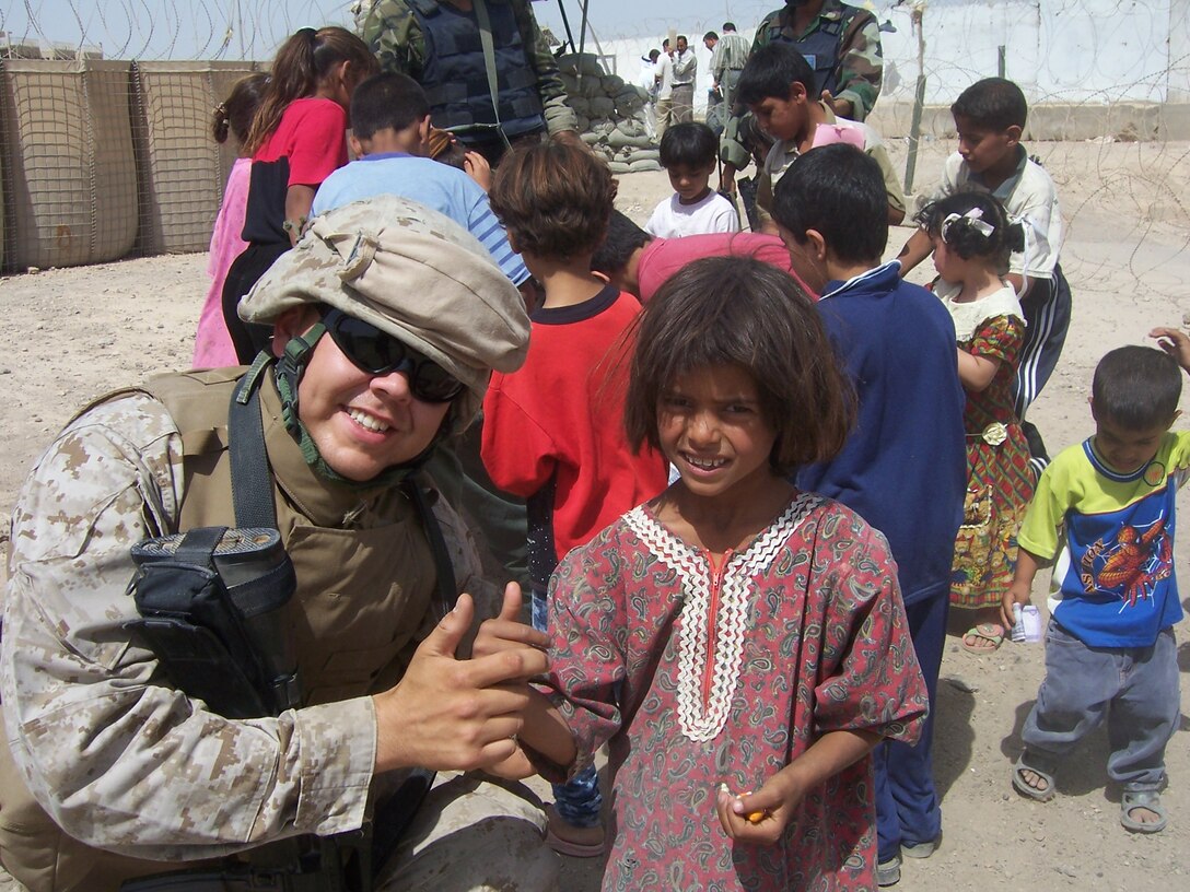 Lance Cpl. Andrew Champion, Chaplain's Assistant, Regimental Combat Team 8, pauses while handing out toys June 14 in Fallujah, Iraq. Champion, of Waltham Mass., coordinates regular distribution of toys, school supplies, and clothing as part of the RCT-8 presence in Fallujah. Generous Americans and family members send these items on a regular basis to Iraq, and the items are sorted and distributed to children.