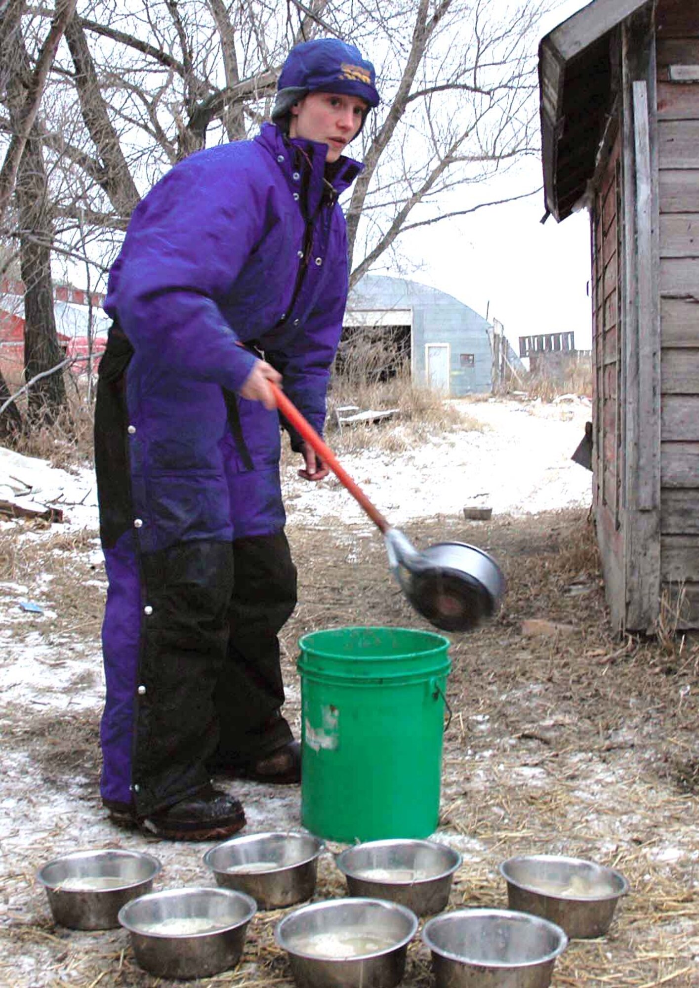 DEERING, N.D. -- Senior Airman Mary Lunde fills up bowls of water for her dogs before taking them for a ride across the snow-covered North Dakota prairie near here.  She owns more than a dozen sled dogs that she trains with weekly in hopes of one day racing in the Iditarod.  Airman Lunde is assigned to the 5th Munitions Squadron at nearby Minot Air Force Base.  (U.S. Air Force photo by Airman 1st Class Danny Monahan)