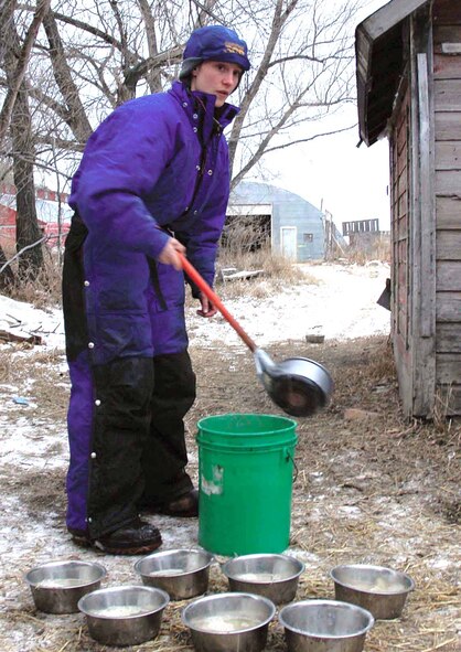 DEERING, N.D. -- Senior Airman Mary Lunde fills up bowls of water for her dogs before taking them for a ride across the snow-covered North Dakota prairie near here.  She owns more than a dozen sled dogs that she trains with weekly in hopes of one day racing in the Iditarod.  Airman Lunde is assigned to the 5th Munitions Squadron at nearby Minot Air Force Base.  (U.S. Air Force photo by Airman 1st Class Danny Monahan)