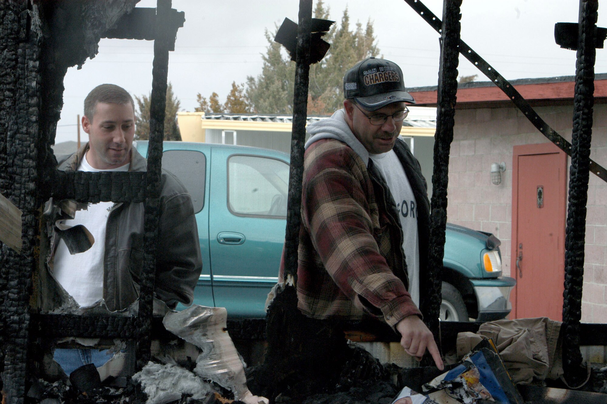 EDWARDS AIR FORCE BASE, Calif. -- Tech. Sgts. Jerry Rocovits (left)  and James Voight survey the damage to burned mobile home Jan. 8 at a trailer park near here.  The Airmen pulled an occupant to safety.  Sergeant Rocovits is a 412th Flight Test Squadron KC-135C Speckled Trout structural repair maintenance specialist, and Sergeant Voight is a 412th Aircraft Maintenance Squadron F-16 Fighting Falcon mechanic.  (U.S. Air Force photo by Senior Airman Matthew Dillier)