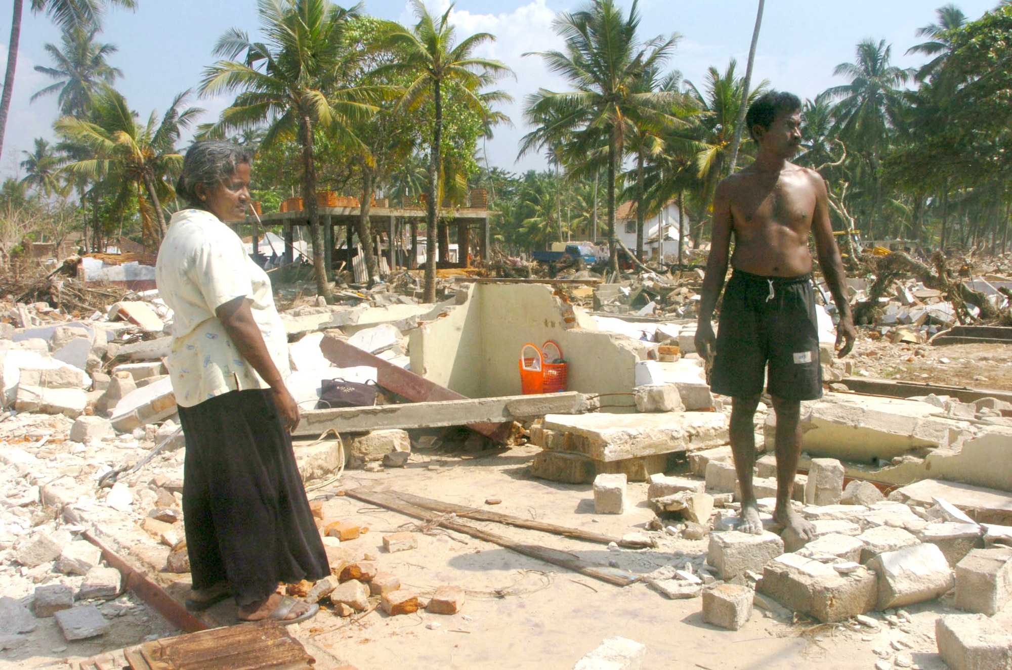 GALLE, Sri Lanka -- K. Rupawathi and her husband A.P. Tudor Jayasekera ponder their future at the ruins here where their home once stood.  The couple lost their home and all their belongings after tsunamis as high as 50 feet devastated their town and swept across coastal areas.  U.S. servicemembers are in the country helping deliver food supplies at various locations.  (U.S. Air Force photo by Master Sgt. Val Gempis)