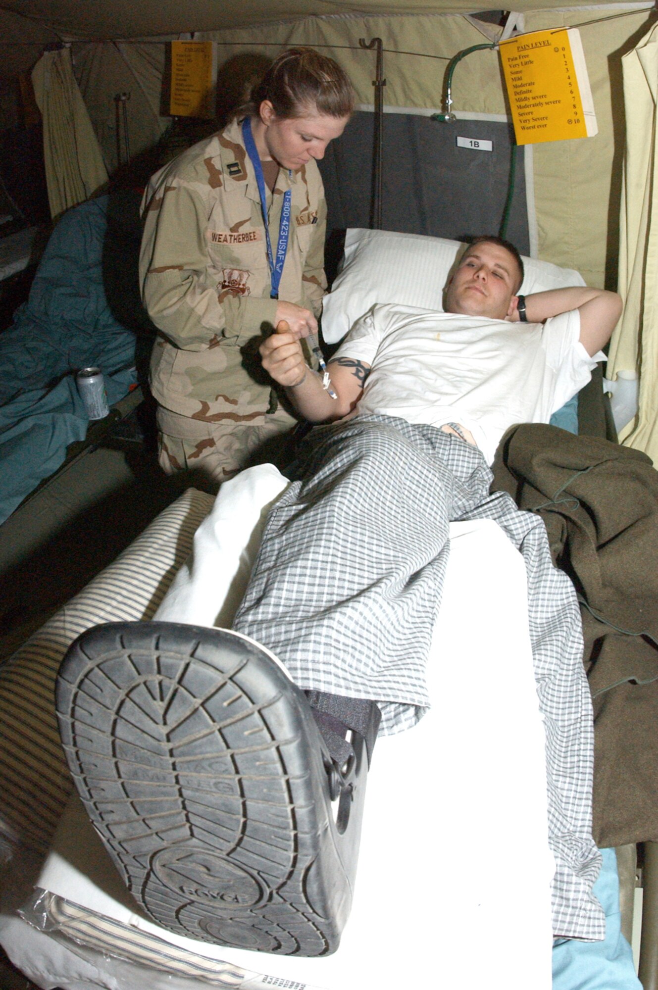 BALAD AIR BASE, Iraq -- Capt. Tamra Weatherbee gives medication to Army Pfc. Matt Baugh at the contingency aeromedical staging facility here Jan. 16.  Captain Weatherbee is a staff nurse at the facility and is deployed from the 859th Medical Operations Squadron at Lackland Air Force Base, Texas.  Private Baugh is a member of the Army's 15th Infantry Division deployed from Fort Lewis, Wash.  (U.S. Air Force photo by Tech. Sgt. Marc Barnes)