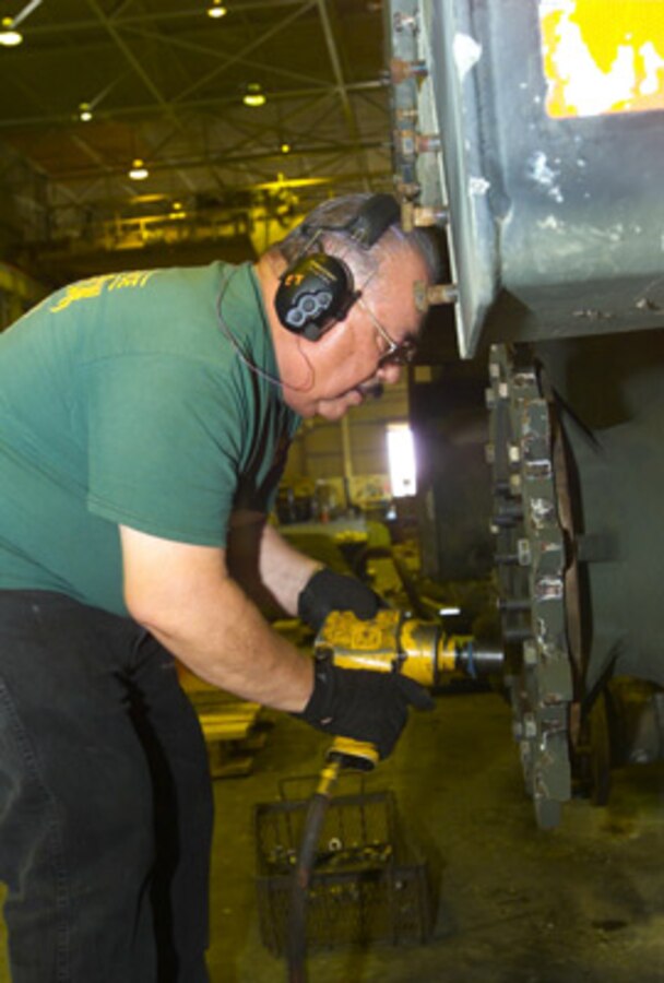 Ed Tintos, heavy mobile equipment mechanic, inserts a bolt into the back sprocket on an M9 Armored Combat Earthmover. Tintos has been working at the maintenance center for 34 years and is considered to be the most experienced M9 ACE mechanic.