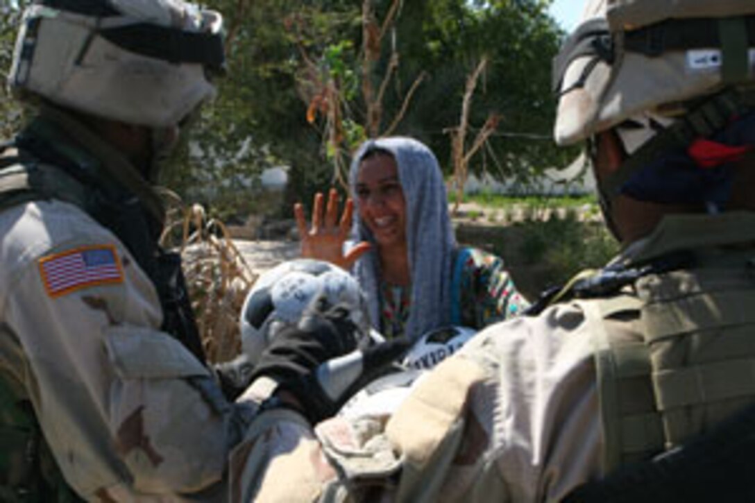 Army Master Sgt. Leon Brown II, 34, team sergeant for 38A Civil Affairs, B Co., 445th Civil Affairs Bn., and native of Milpitas, Calif., gives new soccer balls to one of the Palestine School teachers.  The school was part of the media tour given March 20, 2005.