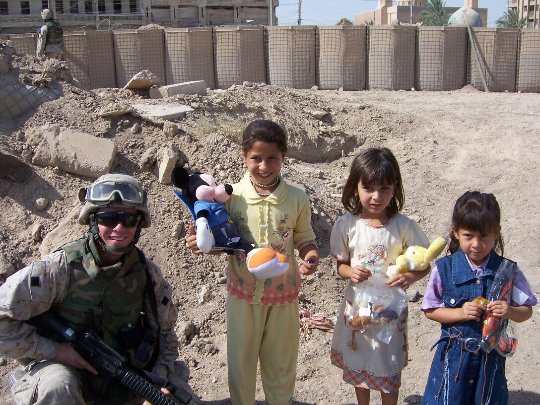 Lance Cpl. Alex Koons of Regimental Combat Team 8 helps pass out toys to the local children of Fallujah on July 21.  Each week the children gather at the Civil Military Operations Center to receive toys from the Marines while waiting for their parents to get their claims.  Due to an endless supply of toys, every week without fail, the Marines bring toys and school supplies donated by Americans.