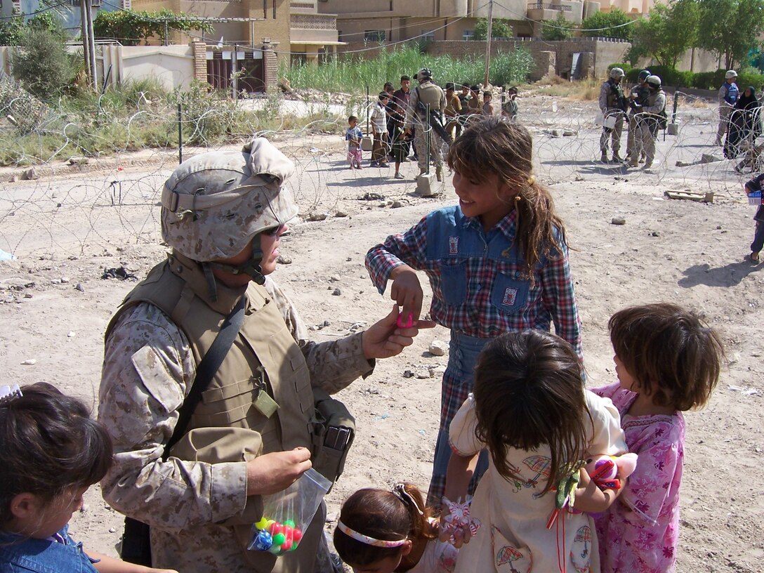Lance Cpl. Andrew Champion, of Regimental Combat Team 8, passes out toys to the children of Fallujah July 21 during his weekly trip to the Civil Military Operations Center.  Nicknamed ?Champs Kids?, this event happens weekly due to countless Americans who donate toys, school supplies, and beanie babies to help bring joy to the children of Fallujah.