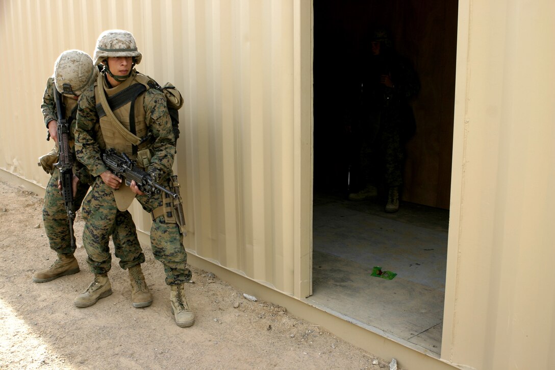 MARINE CORPS AIR-GROUND COMBAT CENTER TWENTYNINE PALMS, Calif. - Private First Class Jorge N. Gabrie, 2nd Platoon, Company A squad automatic weapon gunner, prepares to enter a room and clear it with a fellow infantryman.  Gabrie practiced such raid maneuvers during Military Operations in Urban Terrain training his unit underwent as part of their Revised Combined Arms Exercise here.