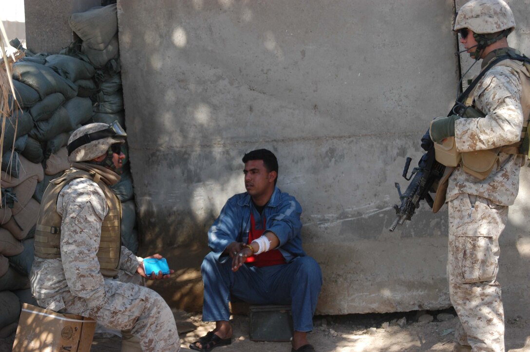 AR RAMADI, Iraq (March 21, 2005) - Fadile, an interpreter for infantry battalion, explains to 20-year-old Lance Cpl. Bradford L. Dunn, squad automatic gunner, 2nd Platoon, Company C, 1st Battalion, 5th Marine Regiment, of Covington, Kan., what an Iraqi man is saying. The man, who was riding a motorcycle, was selected to have his vehicle searched at the entry control point set up on the edge of the South Bridge here. The search criterion for the day was farm equipment and motorcycles. Marines with Company C, 1st Battalion, 5th Marine Regiment, and ISF Commandos conduct random vehicle searches at the ECP, which is located between Marine Camps Snake Pit and Hurricane Point, around the clock in an effort to prevent explosives and weapons from being brought into the city. The Marines are currently the over watch for the ISF Commandos as they conduct the searches. Between 500 and 1000 vehicles enter the city through the ECP each day. Photo by Cpl. Tom Sloan