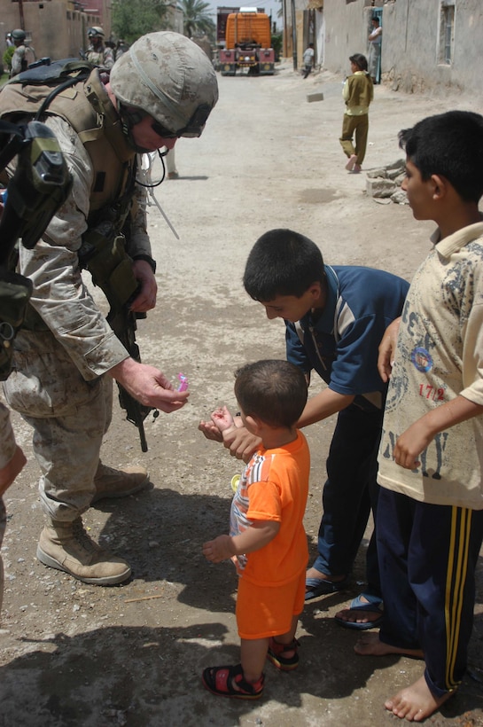 AR RAMAMDI, Iraq (May 21, 2005) -Corporal Clint J. Hurda, squad leader for 2nd Squad, 1st Platoon, Company C, 1st Battalion, 5th Marine Regiment, gives an Iraqi toddler some candy during a mission in the city here. The 27-year-old from Mineral Point, Wis., and his fellow 2nd Squad leathernecks often carry candy and other gifts with them to give to Iraqi children when they patrol though their neighborhoods. Photo by: Cpl. Tom Sloan