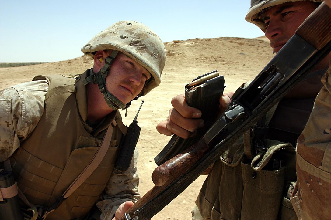 Camp Ripper, Al Asad, Iraq (May 21, 2005) -  A member of the reconnaissance company of the 7th Iraqi Security Battalion waits while his weapon is cleared by RCT-2 insturctor Sgt. Andrew J. Wittmer, 25-year-old Peroria, Illi., native.  (Official USMC photo by Cpl. Ken Melton)