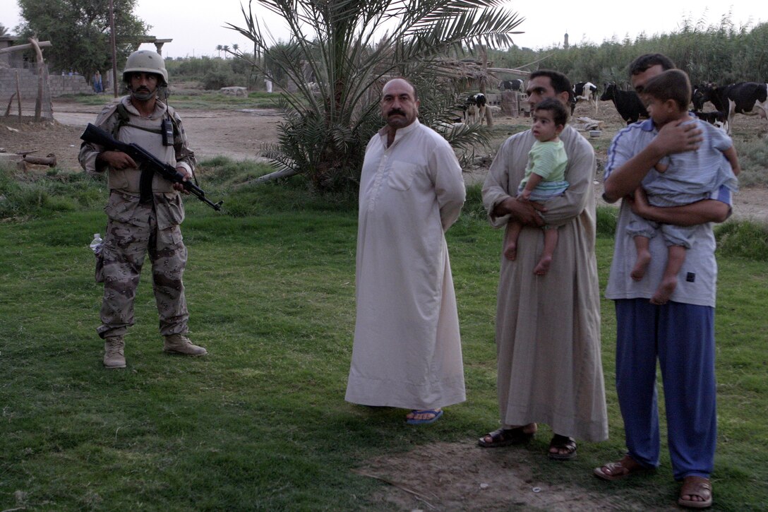 SAQLAWIYAH, Iraq - An Iraqi soldier provides guards residents outside a home here July 21 during Operation Hard Knock, while U.S. Marines search inside the home.  Iraqi Security Forces worked alongside Company A, 1st Battalion, 6th Marine Regiment personnel to sweep through northern Saqlawiyah's Al Zakarit district to look for weapons and insurgent activity, as well as gather census information on the populace.