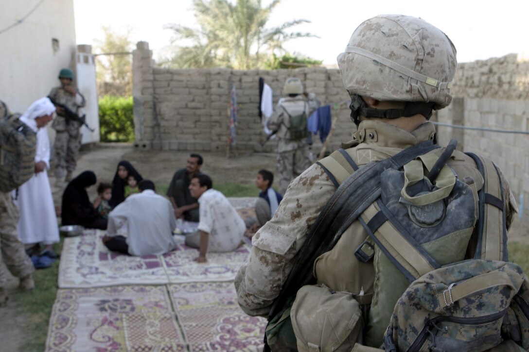 SAQLAWIYAH, Iraq - A Marine with 4th Platoon, Company A, 1st Battalion, 6th Marine Regiment provides security outside a local residency here July 21 during Operation Hard Knock, while fellow Marines and Iraqi soldiers speak with some citizens.  Company A personnel worked alongside Iraqi Security Forces to sweep through northern Saqlawiyah's Al Zakarit district to look for weapons and insurgent activity, as well as gather census information on the populace.