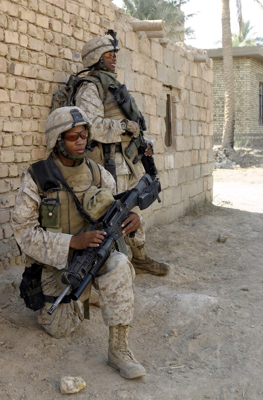 SAQLAWIYAH, Iraq - Cpl. Jovan Riley, an infantryman with 4th Platoon, Company A, 1st Battalion, 6th Marine Regiment, front, and Lance Cpl. Clinton Fort, a fellow infantryman, provide security outside a residence here July 21 during Operation Hard Knock.  Company A personnel worked alongside Iraqi Security Forces to sweep through northern Saqlawiyah's Al Zakarit district to look for weapons and insurgent activity, as well as gather census information on the populace.