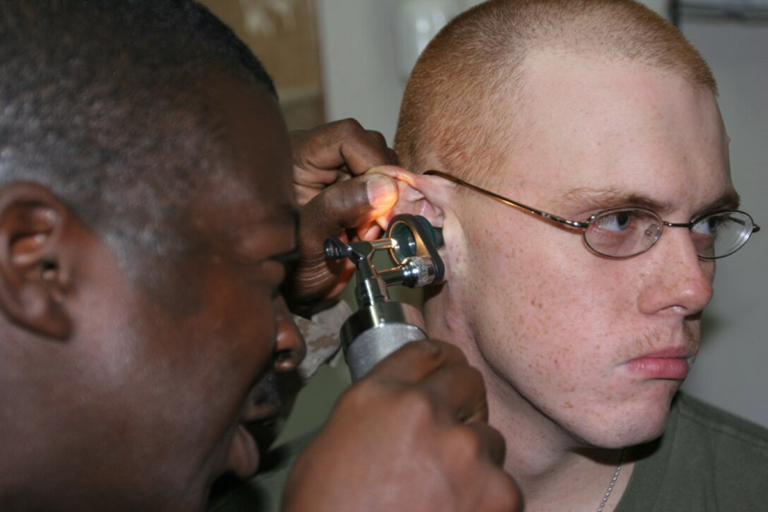 050917-M-2607O-003 CAMP FALLUJAH, Iraq -- Navy Chief Petty Officer Lester M. Wellmaker, battalion medical chief, 2d Battalion, 2d Marine Regiment, checks the ear of a patient during morning sick call at the Battalion Aid Station on Camp Fallujah.  The corpsmen and the BAS handle almost all the medical issues for the battalion unless they need to get higher medical attention.