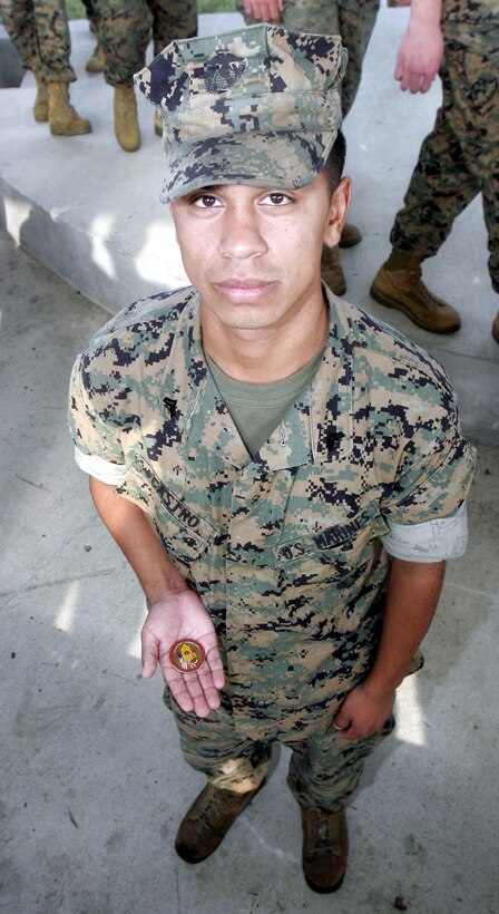 Cpl. Louie Castro, 21-year-old Fresno, Calif. native and battery clerk, Battery F, holds a coin awarded to him by Sergeant Major of the Marine Corps Sgt. Maj. John L. Estrada upon the occasion of Estrada's visit here October 21. He stressed the importance of noncommissioned officer leadership, retention and off-duty safety considerations to several units around base. "[Marines today] have knowledge and experience in combat that Marines haven't had in a long time," Estrada said.