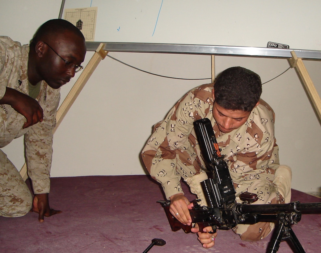 CAMP HABBANIYAH, Iraq - Sergeant Marcus Bryant, an instructor for the Iraqi Small Arms Weapons Instructors Course and MUX operator for the 2nd Marine Division Training Center here, watches as an Iraqi Soldier practices assembling and disassembling the PKM medium machine gun.