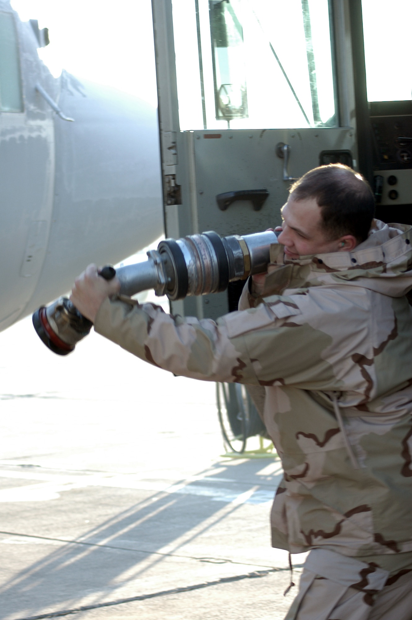 KARSHI-KHANABAD AIR BASE, Uzbekistan -- Senior Airman Seth Rindo pulls a fuel hose from a fuel truck to refuel a C-130 Hercules here Jan. 19.  He is a fuels distribution journeyman deployed from Grand Forks Air Force Base, N.D., to the 416th Expeditionary Mission Support Squadron fuels management flight here.  (U.S. Air Force photo by Tech. Sgt. Scott T. Sturkol)
