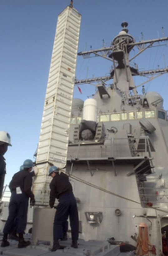 Sailors aboard the guided missile destroyer USS Curtis Wilbur (DDG 54) stabilize a shipping container holding a Tomahawk cruise missile as it is lifted off the ship by a crane on Jan. 10, 2005, in Yokosuka, Japan. The missile, along with other shipboard ammunition, is being removed in preparation for an upcoming selected restricted availability period in which the vessel will undergo major renovations and overhauls, increasing its capabilities. 