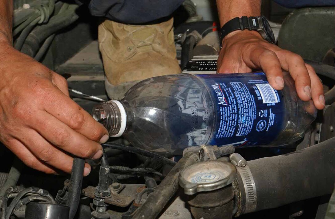 The Combat Service Support Company-133 maintenance Marines use a bottle of water to trouble shoot a fuel injection pump inside a high-mobility, multipurpose wheeled vehicle at Site 50 during the Weapons and Tactics Instructor Course April 6.