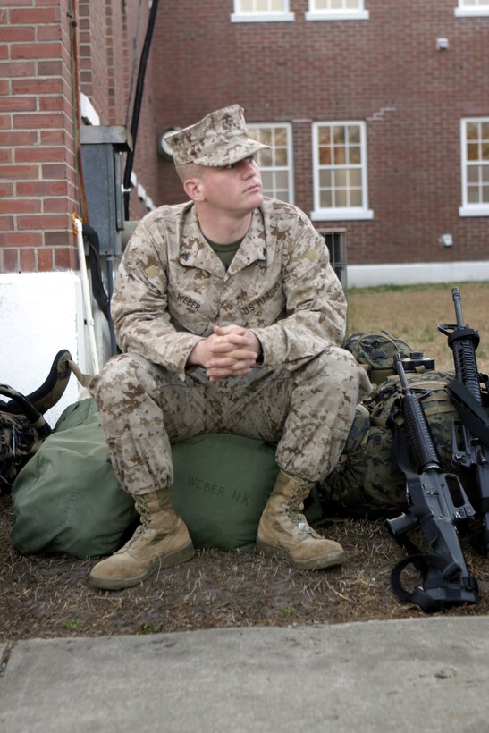 MARINE CORPS BASE CAMP LEJEUNE, N.C. - Cpl. Nicholas K. Weber, radio technician with 1st Battalion, 6th Marine Regiment and Louisville, Ky. native, sits atop his duffel bag as he waits to board a bus.  Weber was one of approximately 50 Marines and sailors to leave here for Iraq as part of 1st Battalion, 6th Marine Regiment's advance party to help pave the way for the arrival of the main body in March.
