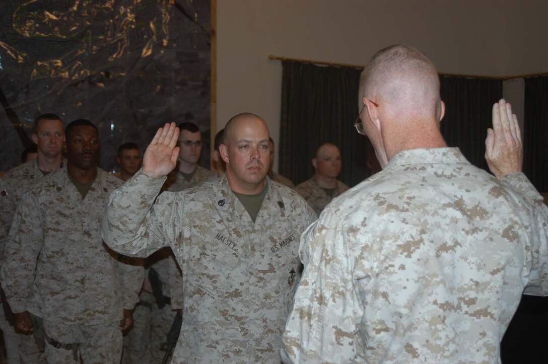 CAMP HURRICANE POINT, Ar Ramadi, Iraq (April 22, 2005) - Staff Sgt. Keith L. Halsey, logistics chief, Headquarters and Service Company, 1st Battalion, 5th Marine Regiment, holds up his right hand and takes his oath of reenlistment from Capt. Daniel H. Coleman, H&S Company's logistics officer, during a ceremony here. Fellow leathernecks with the infantry battalion attended to honor the 30-year-old Syracuse, N.Y., native on his special day. Halsey has been proudly wearing the Eagle, Globe and Anchor for the past decade and plans on serving for another 10 years. Photo by Cpl. Tom Sloan