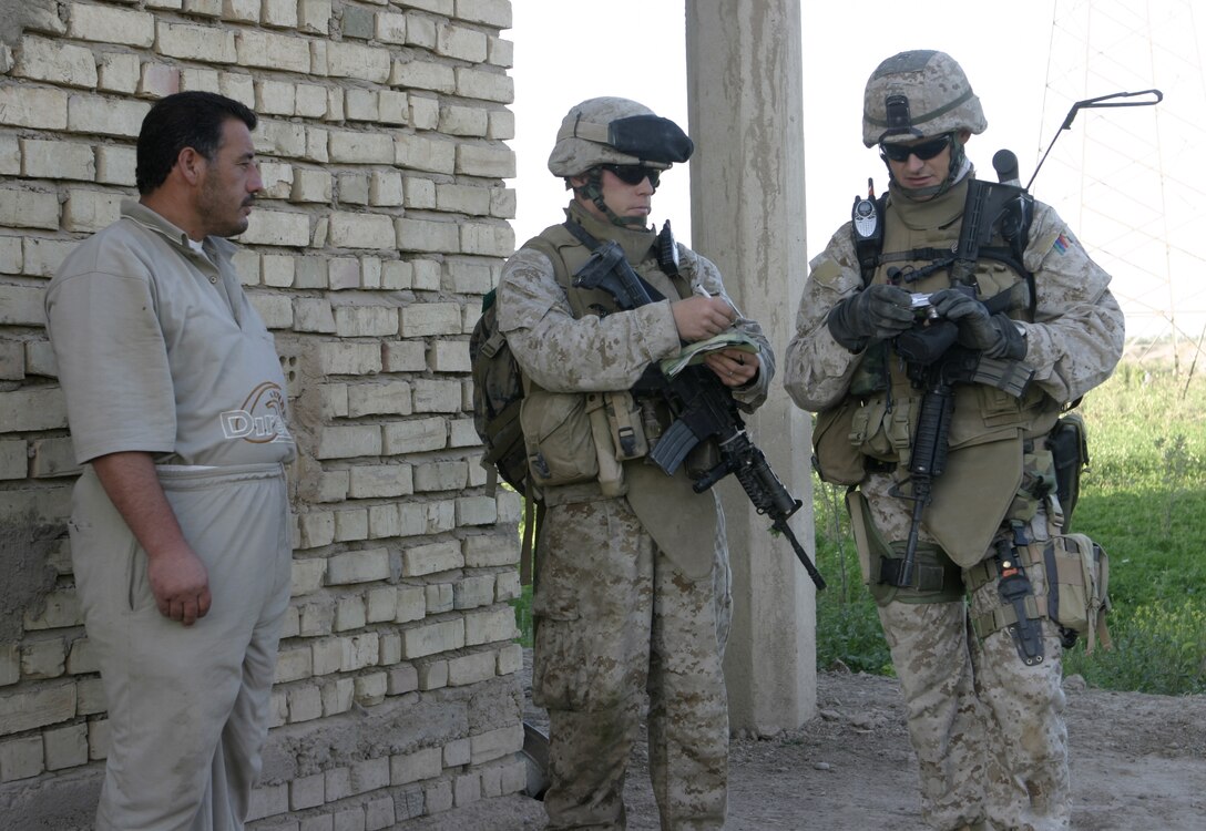 SAQLAWIYAH, Iraq - Staff Sgt. Jason Rockwell, 2nd Platoon sergeant, Company A, 1st Battalion, 6th Marine Regiment, right, and Cpl. Mark Duncan, 3rd Squad leader, 2nd Platoon, left, speak with a farmer in a field outside Saqlawiyah May 22.  Company A personnel worked alongside Iraqi soldiers and combat engineers to sweep through numerous farm fields outside Saqlawiyah, looking for hidden weapons caches and insurgent activity.