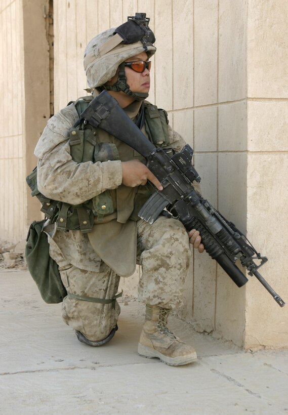 THAR THAR REGION, Iraq - Lance Cpl. Bee Thao, an infantryman with 2nd Squad, 2nd Platoon, Company B, 1st Battalion, 6th Marine Regiment, provides security alongside a ruined building wall here June 18.  Thao's unit was one which participated in Operation Dagger, a five-day long effort to rid regions north of Fallujah of insurgent activity.