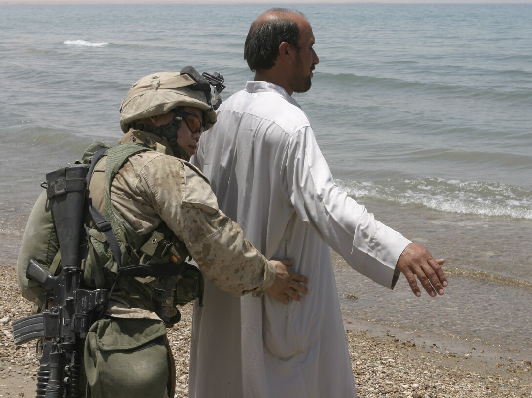 THAR THAR REGION, Iraq - Lance Cpl. Bee Thao, an infantryman with 2nd Squad, 2nd Platoon, Company B, 1st Battalion, 6th Marine Regiment, searches a fisherman for weapons on the Thar Thar Lake shoreline June 18.  Thao's unit was one which participated in Operation Dagger, a five-day long effort to rid regions north of Fallujah of insurgent activity.