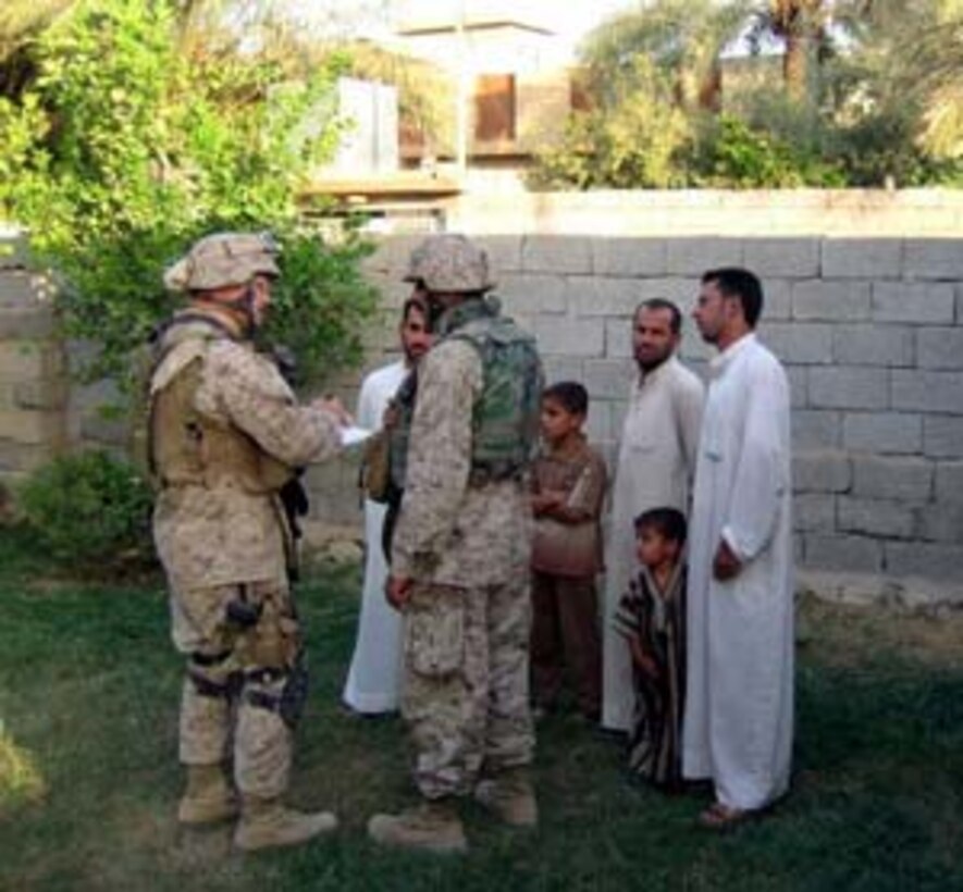During his first week in Iraq, Maj. David Lofgren, a 6th Civil Affairs Group team leader, speaks with three Iraqi nationals through a translator about local conditions and the upcoming Constitutional referendum election occurring Oct. 15.  The 6th CAG officially took over from 5th CAG on Sept 21, 2005.